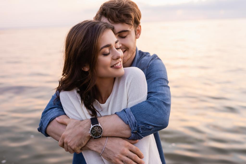 stock photo young man hugging brunette girlfriend closed eyes sea sunset